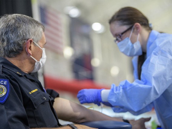 A health care worker prepares to apply a bandage to a police officer who has been tested.