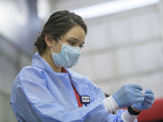A health care worker examines a vial of blood that will be sent to a lab to be tested.