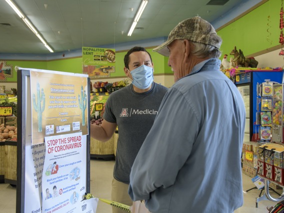 Ricardo Reyes, a College of Medicine – Tucson student, speaks with a customer at a Food City grocery store in Tucson about the social distancing campaign he and his classmates have created to inform the Spanish-speaking community. 