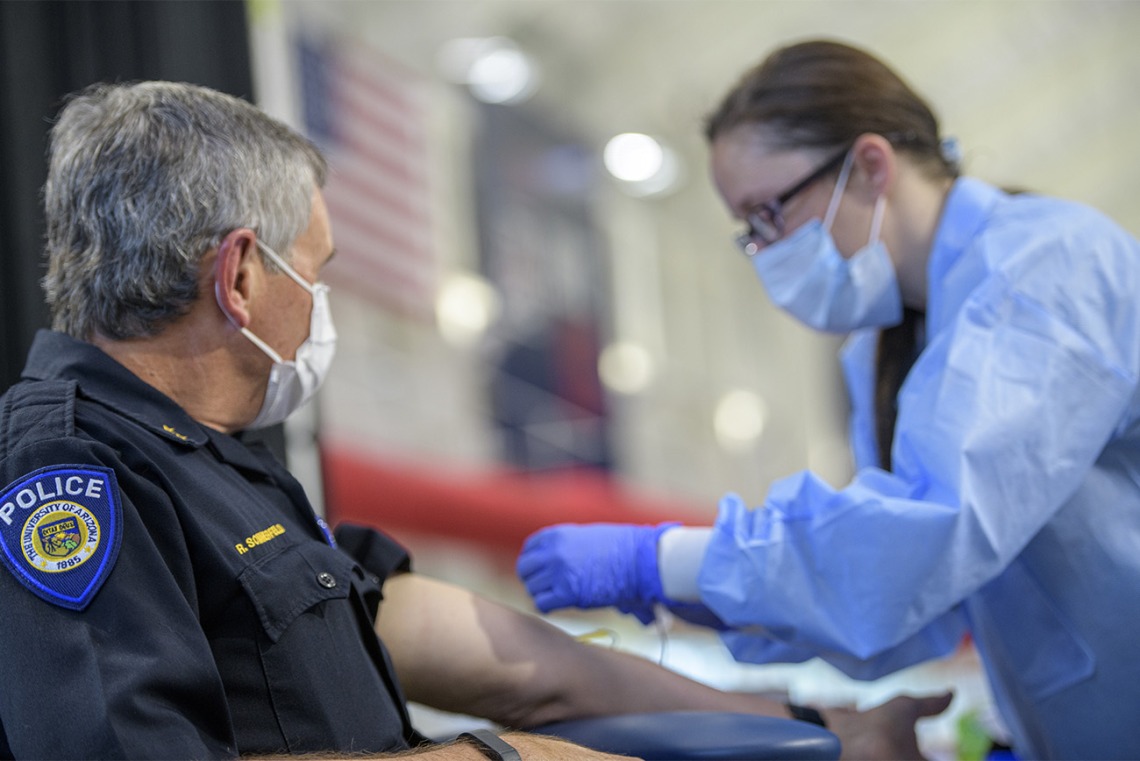 A health care worker prepares to apply a bandage to a police officer who has been tested.