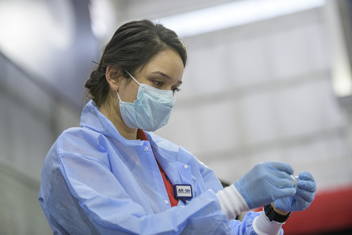 A health care worker examines a vial of blood that will be sent to a lab to be tested.