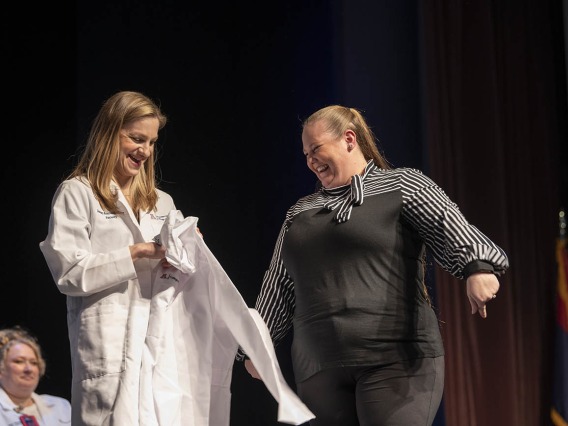 Professor Lindsay Bouchard presents Pamela Michel her coat at the UArizona College of Nursing white coat ceremony.