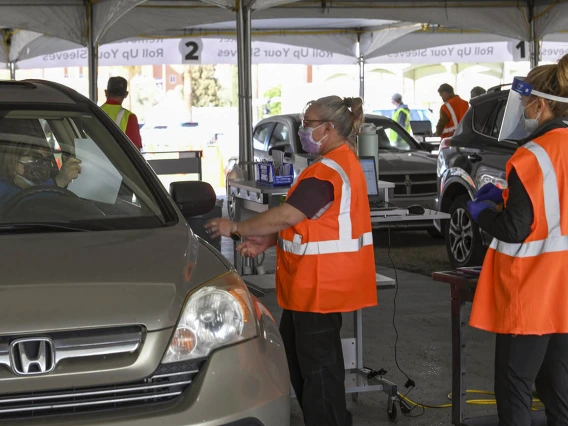 Volunteers Becky Dillie, center, Kerry Johnson, right, collect paperwork from drivers awaiting their vaccine.