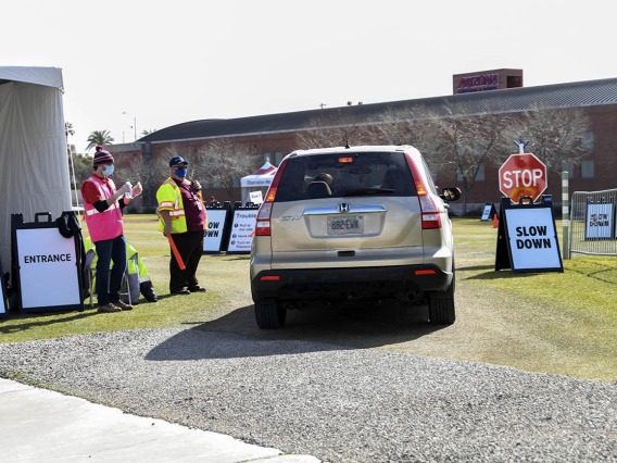 Brandon Goldstein, left, and Mike Wallace greet and direct drivers in the post-vaccine observation parking lot.