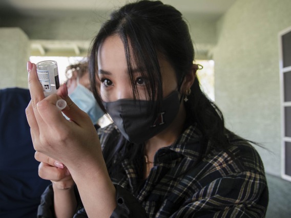 Second-year College of Pharmacy student Lisa Wan prepares to vaccinate a patient against the virus that causes COVID-19.