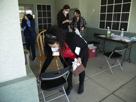 Maria Jaime, health educator from the College of Public Health in Phoenix, sanitizes a chair before the next patient sits down to receive the COVID-19 vaccine.