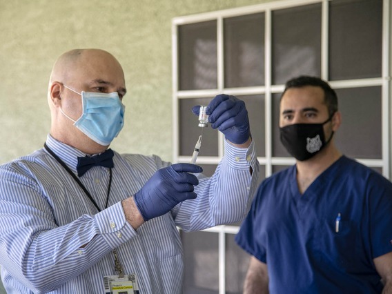 Jim Lindgren, MD, director of simulation curriculum and clinical assistant professor at College of Medicine – Phoenix, prepares a vaccine as Jeffery Hanna, clinical research coordinator, observes.