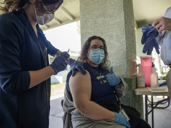 Shae Corea, a health care navigator for El Mirage Senior Village, gives a thumbs up before she receives the COVID-19 vaccine.