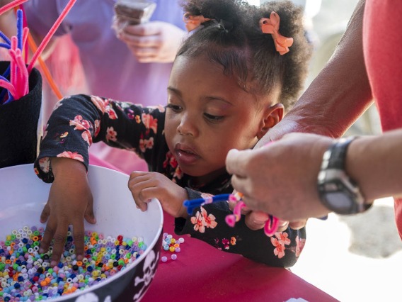 Ar'jianna Roberts grabs beads to put on the spider she made during the recent Family SciFest at Children's Museum Tucson.