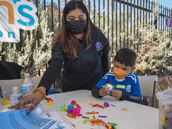 Medical Directive student Sakshi Akki gets a coloring booklet for Jay Mendoza while he makes a model of a virus during the recent Family SciFest at Children's Museum Tucson.