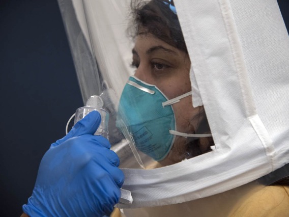 Bitters are sprayed directly toward College of Medicine – Tucson second-year student Sanga Shir, who is decked out in a hooded mask and N95 respirator.