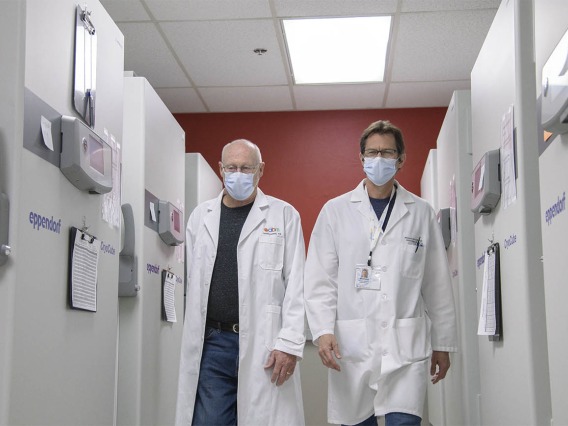 Drs. David Harris and Michael Badowski walk through the freezer farm to collect more vaccines for distribution.