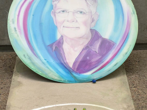 Dianne Post (1947) — Dianne Post is a lawyer who advocates for the rights of women, primarily fighting poverty and injustice in the world stemming from the inequality of women in society. Post is an expert in gender-based violence against women and children, including domestic violence, sex-trafficking, prostitution and pornography. (Acrylic paints with a resin finish on a metal backing for the portrait; base is plywood with a cement finish and acrylics, by Suzanne Whitaker)