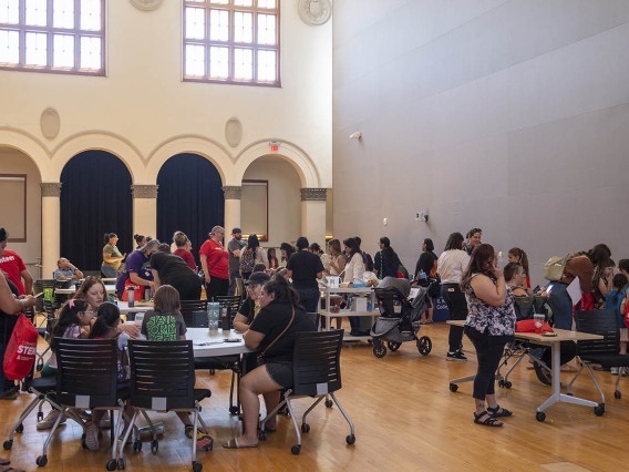 A big room filled with activity tables, girl scouts and adults all engaged with each other.