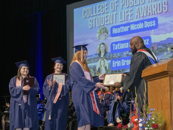 (From left) Heather Nicole Doss, MPH, Tatiana Gonzalez, MPH, and Erin Green receive Student Life Awards from Andre Dickerson, MA, MBA, assistant dean of student services and alumni affairs, during the 2022 Mel and Enid Zuckerman College of Public Health spring convocation.