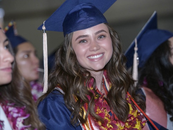 Edda Anderson wears a graduation lei with the traditional cap and gown as she waits to cross the Centennial Hall stage to receive a bachelor’s degree at the 2022 Mel and Enid Zuckerman College of Public Health spring convocation.