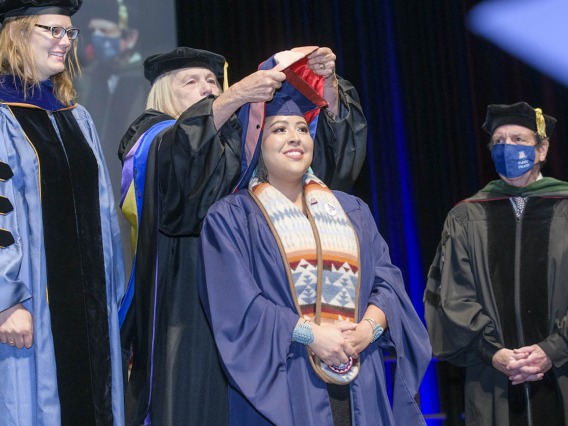 Carol Seanez, MPH, is hooded during the 2022 Mel and Enid Zuckerman College of Public Health spring convocation.