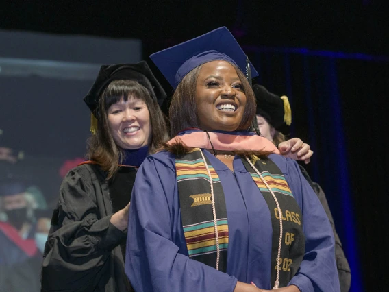 Master of Public Health student Eniola Idowu, MPH, is hooded during the 2022 Mel and Enid Zuckerman College of Public Health spring convocation.
