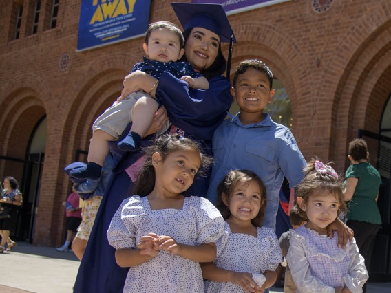 Josselyn Sanchez, MPH, poses with her nephews and nieces outside of Centennial Hall after the 2022 Mel and Enid Zuckerman College of Public Health spring convocation.