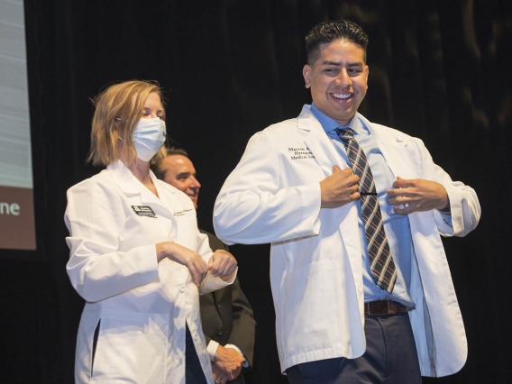 Marvin Alfredo Hernandez receives his white coat from UArizona College of Medicine – Phoenix Associate Dean of Student Affairs Stephanie Briney, DO, during the Class of 2026 white coat ceremony.