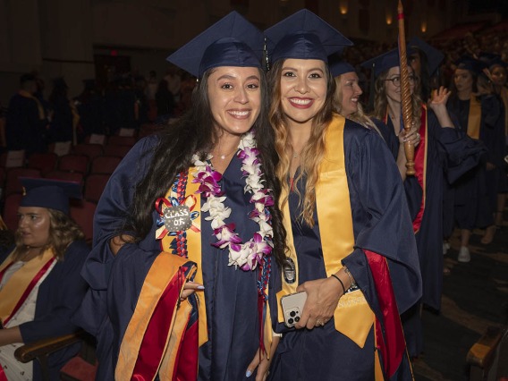 Yesenia Ordaz (left) and Raquel Mendoza, both Master of Science Entry to the Nursing Profession students, pause for a photo while going to their seats in Centennial Hall before the College of Nursing 2022 summer convocation.