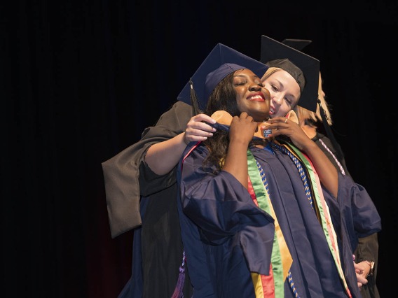 Master of Science in Nursing Entry to the Profession student Rosine Laure Bouguem is hooded by Carrie Van Bakel, MSN, during the College of Nursing’s 2022 summer convocation.