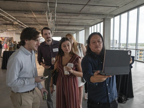 Artist Rembrandt Quiballo (right) demonstrates his augmented reality artwork, “It’s All in Your Head—Deconstructing the Brain Concussion” that he created based on research done by Theresa Currier Thomas, PhD, an associate professor in the College of Medicine – Phoenix, during the Artist + Researcher VIP exhibition.