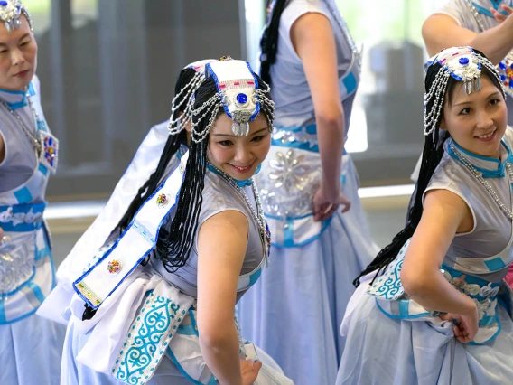 Three women wearing fancy traditional Chinese dance costumes perform a dance. 