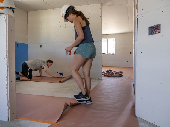 Nolan Lassiter, DO, (in background) and Veronica Cheng, MD, both first-year emergency medicine residents at Banner – University Medical Center Tucson, cover the floor of a new Habitat for Humanity Tucson home with protective paper during the EM Day of Service.