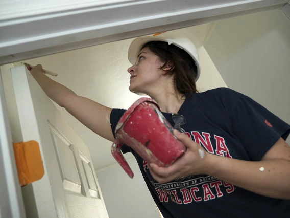 Alex Barbosa, MD, a third-year emergency medicine resident at Banner – University Medical Center Tucson, paints the door jamb of a Habitat for Humanity Tucson home during the EM Day of Service.