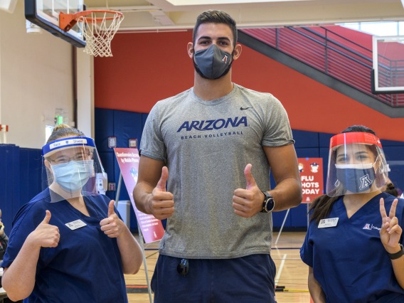 Chase Jones, who is in the University of Arizona men’s indoor volleyball club (center), poses with College of Nursing master’s degree students Hailey Finn (left) and Michelle Garcia (right) at the student-run flu shot clinic.