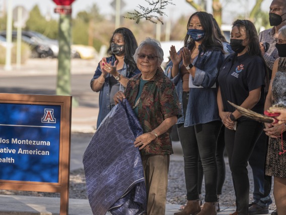 Jennie Joe, PhD, MPH, professor emerita, Family and Community Medicine, smiles after revealing the sign for the newly named Wassaja Carlos Montezuma Center for Native American Health in late October. 