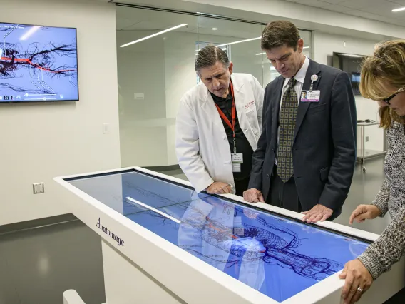 From left: Allan Hamilton, MD, executive director of ASTEC, Kevin Moynahan, MD, College of Medicine – Tucson deputy dean for education, and Deana Ann Smith, BS, BSN, RN, healthcare simulation educator, work on a life-size virtual dissection table. 