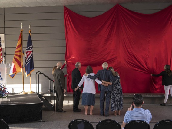 UArizona President Dr. Robert C. Robbins, College of Pharmacy Dean Dr. Rick G. Schnellmann, R. Ken Coit and his family watch the unveiling of the newely named R. Ken Coit College of Pharmacy.