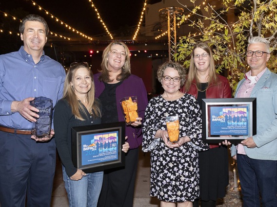 From left: Associate Vice President for Communications, Mark Lane, with members of the Health Sciences Office of Communications staff Kris Hanning, Lesley Merrifield, Caroline Berger, Stacy Pigott and Gawain Douglas hold up the five awards received at the annual Public Relations Society of America – Southern Arizona IMPACT Awards ceremony.