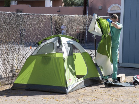 Chris Vance helps set up a tent at the Z Mansion in downtown Tucson. Homeless individuals with potential or suspected coronavirus infection are isolated outdoors in tents on the property. These makeshift “wards” are staffed by UArizona medical students, who distribute food three times a day and monitor patients for worsening conditions.  