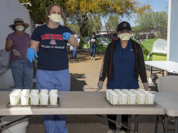 College of Medicine – Tucson students Erika Krall and Dori Lin pour drinks to serve to homeless people during an outreach program to provide medical care to the vulnerable homeless population.