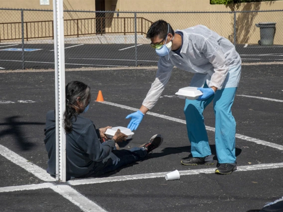 Medical student Christian Bergman offers food to a person at Z Mansion, a soup kitchen for homeless people several times a week.