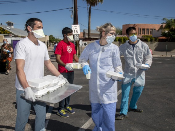 Medical students Jaime Contreras, Shrey Goel and Christian Bergman prepare to distribute food and drinks to homeless residents in Tucson who visit the Z Mansion soup kitchen. The students are also offering a medical clinic to help the vulnerable population during the global pandemic of COVID-19.