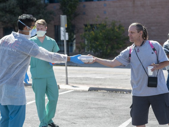 Medical students Christian Bergman and Chris Vance try to keep a safe distance to protect the homeless population they serve during the Commitment to Underserved People’s clinic at a soup kitchen in downtown Tucson.