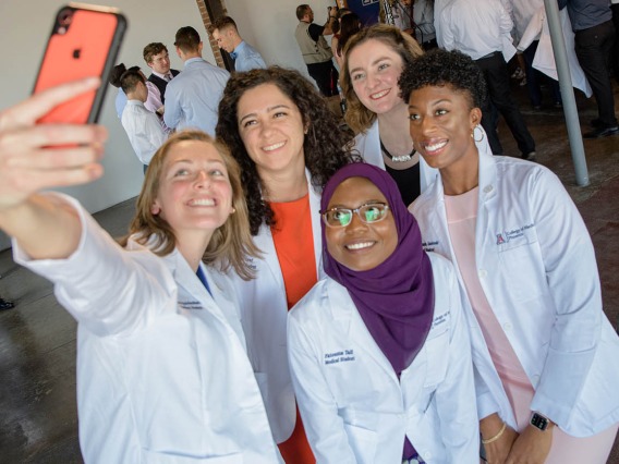 Rachel "R" Reichenbach, Theresa Riley, Fatouma Tall, Rose Graf and Shannon Alsobrooks take a group selfie while sporting their new white coats.