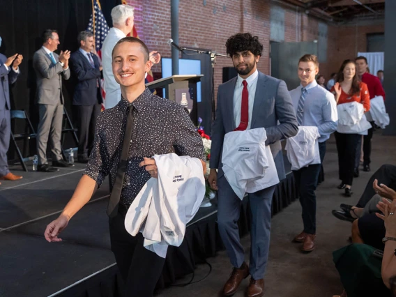 Austin Sherwood, Gurkaran Singh, Jack Stearns, Paige Steffen and Jake Stenzel cross in front of the stage on the way to their seats at the beginning of the ceremony.