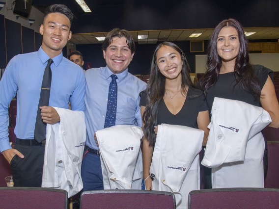 Medical students Brandon Zhang, Luis Novelo Hernandez, Nicole Kummet, and Emily Dereskiewicz pose for a photo before the start of the Class of 2025 white coat ceremony at Centennial Hall.