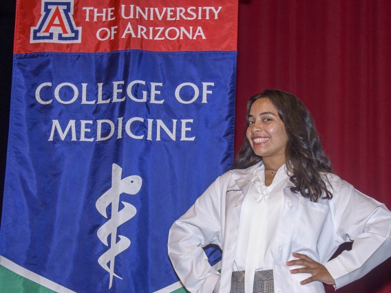 Gisselle Pegaitaz poses in front of the UArizona College of Medicine – Tucson banner after receiving her white coat. 