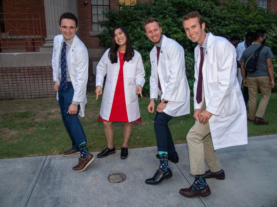 Newly “white-coated” medical students, from left, Riley Hellinger, Coco Victoria Gomez Tirambulo, Mathew Flower and Zak Webber show off their “doctor” socks. 