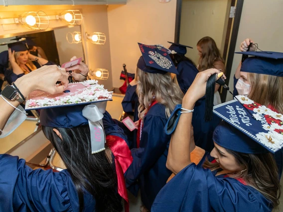 Graduates arrange their highly decorated graduation caps before the start of the college’s August commencement ceremony.