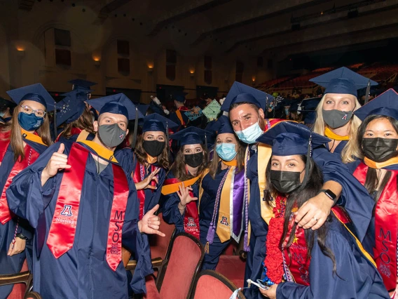 Graduates pose after commencement at Centennial Hall.