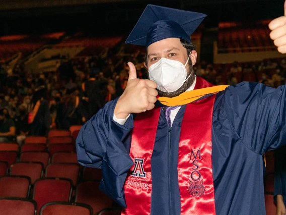 A graduate gives the thumbs up as he exits after the August commencement at Centennial Hall.