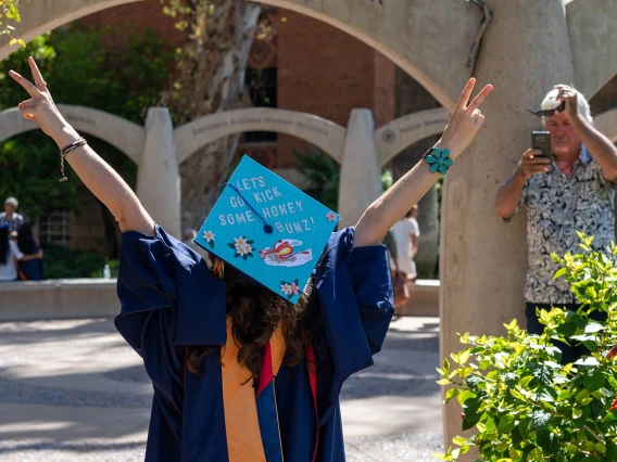 Hailey Sexton raises her arms victoriously after the College of Nursing graduation ceremony.