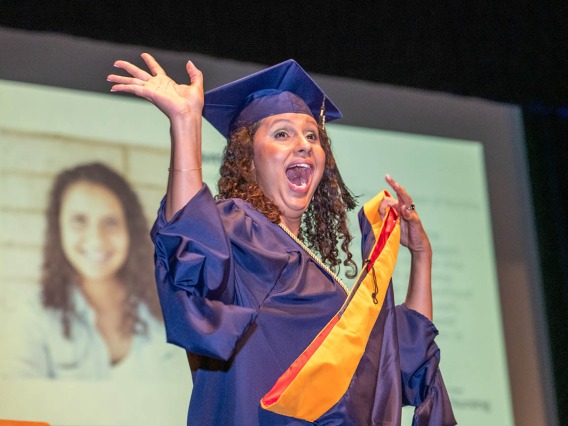 Asma Isack waves to the crowd during the College of Nursing’s August commencement at Centennial Hall.